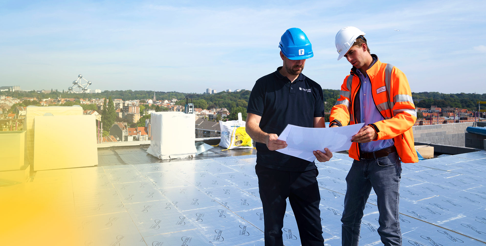 Op de site Hippodroom in Laken plaatsen Tectum Dekkers dakwerkers Recticel plat dak afschotisolatie met zicht op het Atomium en de basiliek van Koekelberg.