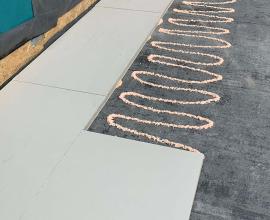 Recticel Insulation's Deck-VQ VIP insulation panel laid on a flat roof partially comple application image with glue